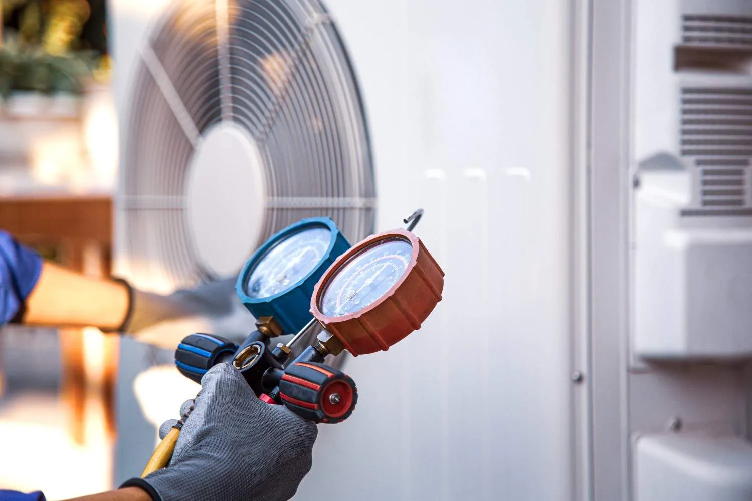 Technician checking an outdoor air conditioning unit with pressure gauges